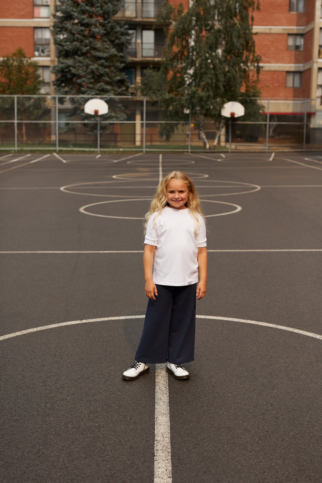 White grow-with-me t-shirt for kids, made from soft organic cotton with a stretchy, foldable waistband. Ethically made in Canada for a sustainable and comfy fit.