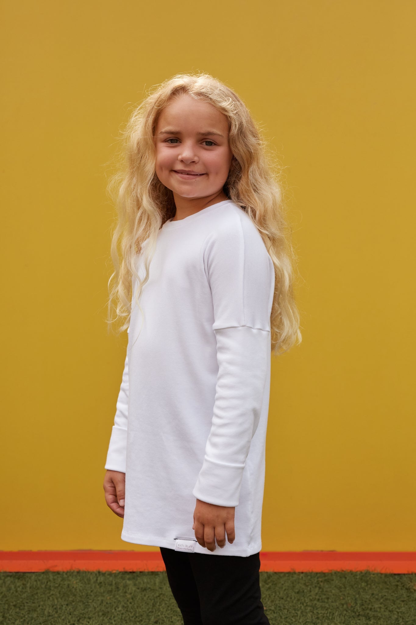 White grow-with-me shirt for toddlers and kids, designed to be worn as a dress, tunic, or long shirt. Seamless shoulders and soft, eco-friendly fabric. Ethically made in Canada.