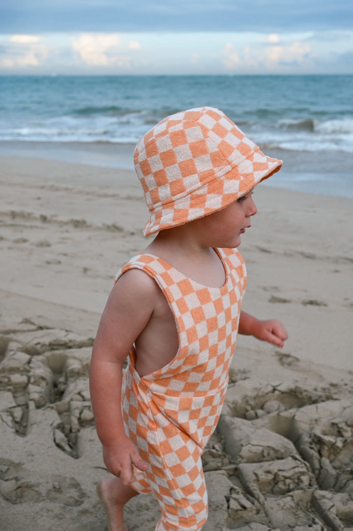 Orange checkered overalls made in Canada with eco-friendly fabric designed to grow with your child
