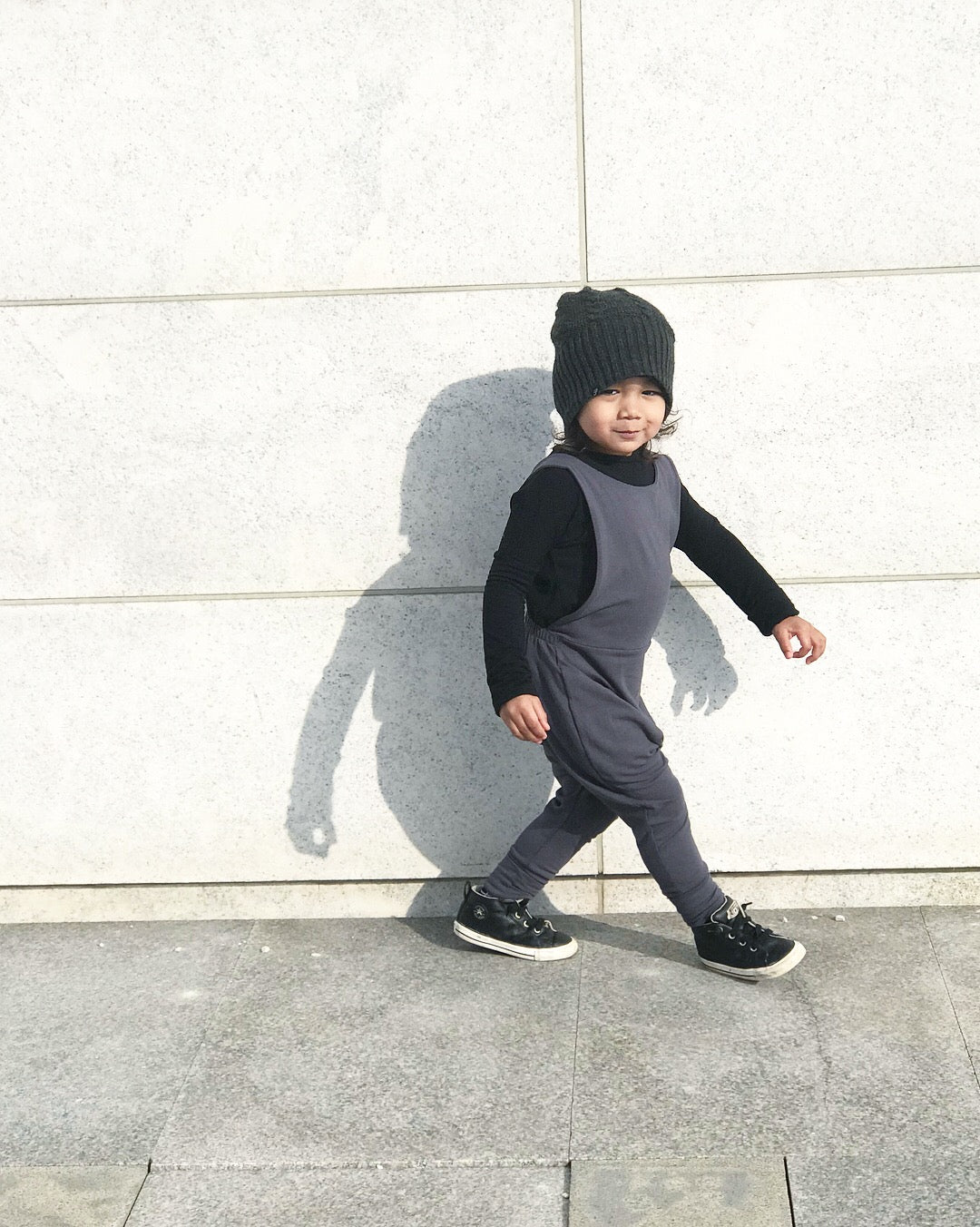 Dark grey grow-with-me overalls for toddlers and kids, made from soft, eco-friendly fabric. Adjustable straps and cuffs for a long-lasting fit. Ethically made in Canada.