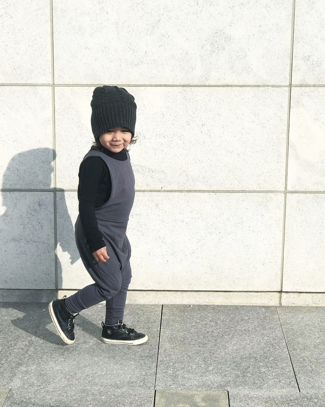 Dark grey grow-with-me overalls for toddlers and kids, made from soft, eco-friendly fabric. Adjustable straps and cuffs for a long-lasting fit. Ethically made in Canada.