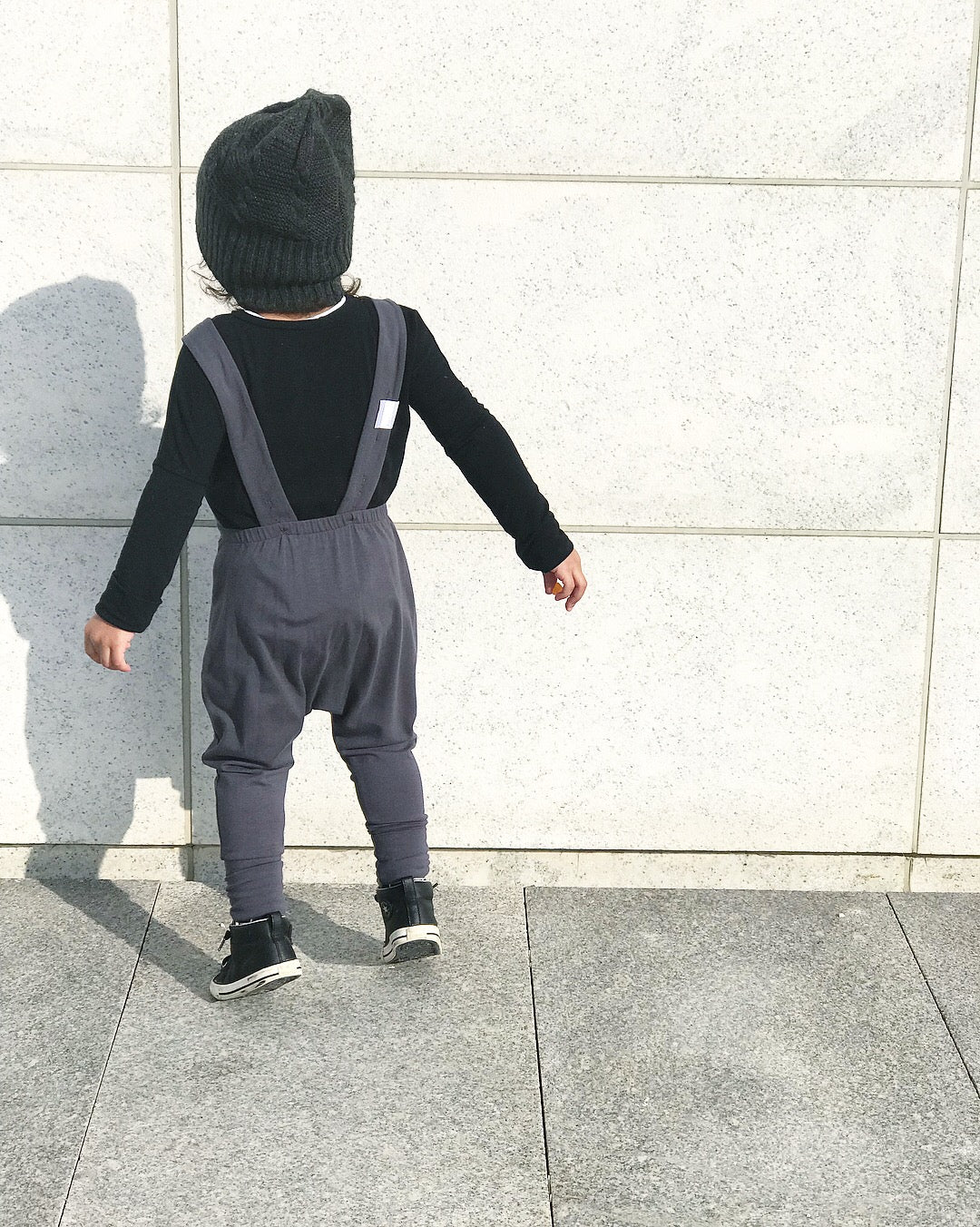 Dark grey grow-with-me overalls for toddlers and kids, made from soft, eco-friendly fabric. Adjustable straps and cuffs for a long-lasting fit. Ethically made in Canada.