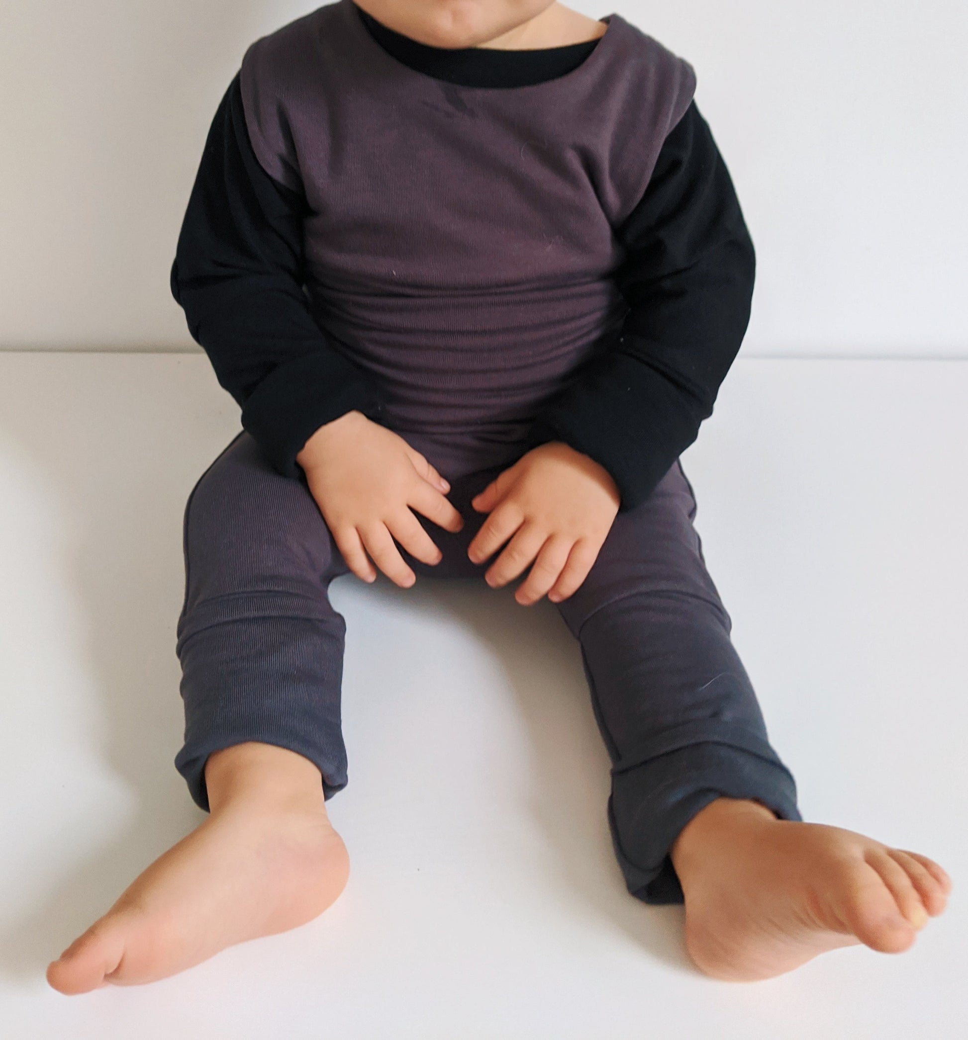 Dark grey grow-with-me overalls for toddlers and kids, made from soft, eco-friendly fabric. Adjustable straps and cuffs for a long-lasting fit. Ethically made in Canada.